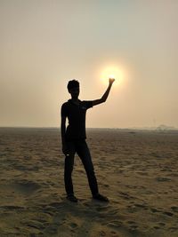 Optical illusion of man holding sun at beach