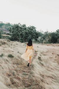 Rear view of woman walking on field