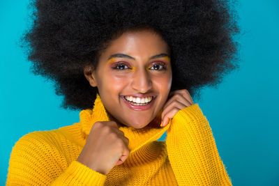 Portrait of smiling young woman against blue background