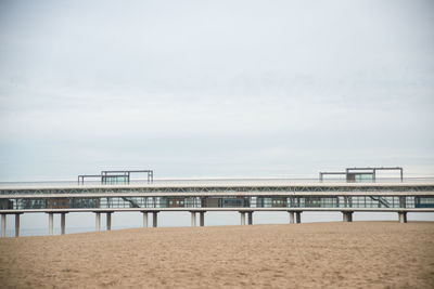 Pier seen from beach against sky