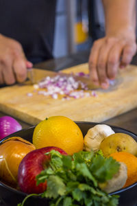 Fruits and vegetable in container with man chopping onion in background