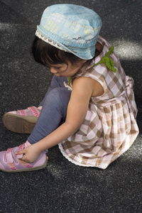 High angle view of girl sitting on road