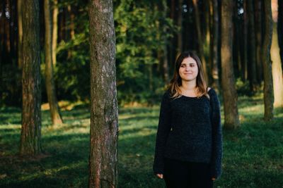 Smiling young woman standing in forest