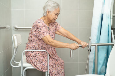 Asian senior woman patient use toilet bathroom handle security concept.