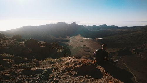 Rear view of woman looking at mountains against sky