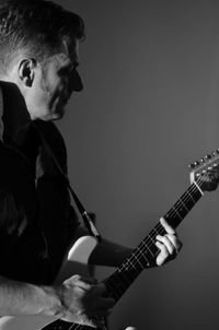 Man playing guitar against gray background