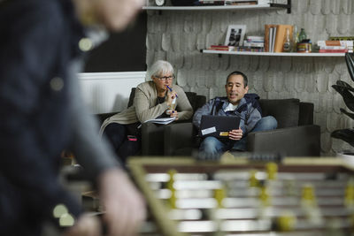 Business people discussing while sitting on sofa at office