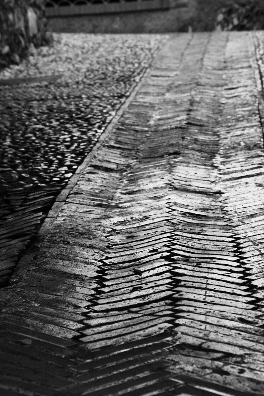 the way forward, surface level, diminishing perspective, textured, high angle view, vanishing point, selective focus, street, transportation, asphalt, close-up, road, outdoors, no people, day, pattern, footpath, sunlight, cobblestone, walkway