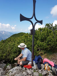 Men wearing at hat sitting by iron cross shape at berchtesgaden alps