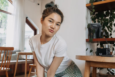Young woman looking away while sitting at home