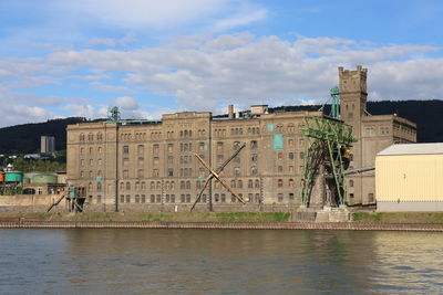 Buildings by river against sky in city