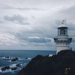 Low angle view of lighthouse by sea against cloudy sky