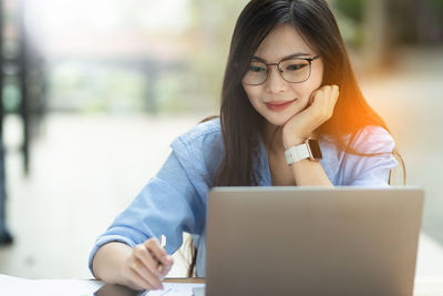 Young woman using laptop while sitting on table