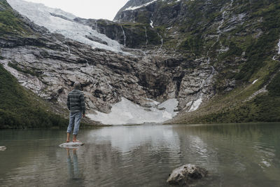 Man standing on rock by lake