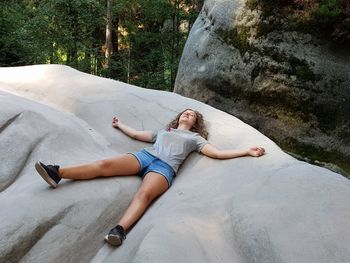 High angle view of carefree teenage girl lying on rock