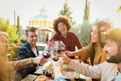 Smiling friends toasting drinks on table