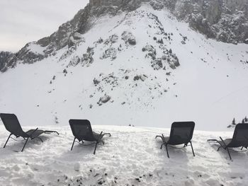 Empty chairs on snow covered land