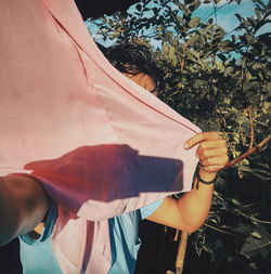 Man covering face while standing against plants