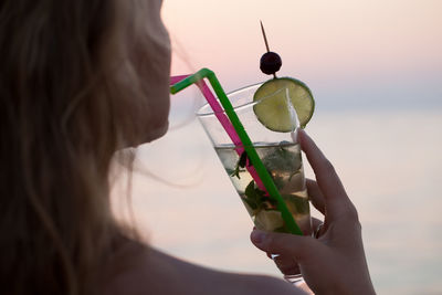 Cropped image of woman drinking cocktail outdoors