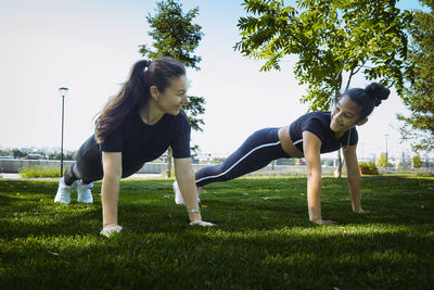 Mom and daughter in sportswear on a sunny summer day on the embankment in the park 