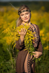 Portrait of young woman standing against plants