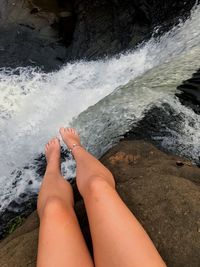 Low section of woman feet on rock by sea