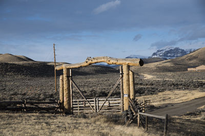 Wooden gate on field against sky