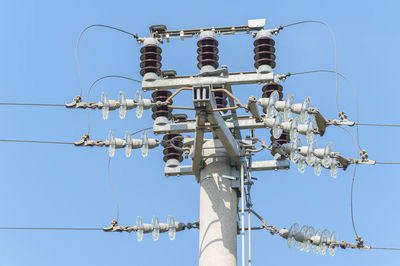 Low angle view of electricity pylon against clear blue sky