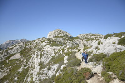 People on mountain against clear blue sky