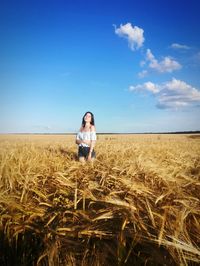 Young woman standing on field against sky