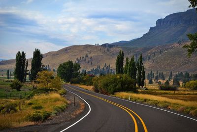 Road leading towards mountains against sky