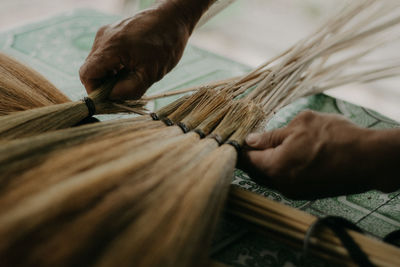 Close-up of person working on handcrafted walis tambo or brooms