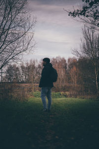 Rear view of man standing on field against sky