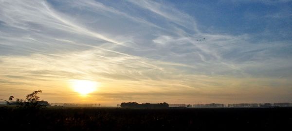 Scenic view of silhouette field against sky during sunset