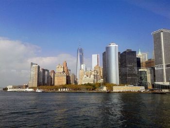 Sea by modern buildings in city against sky