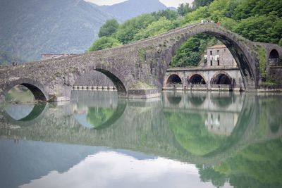 Arch bridge over lake against mountain