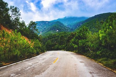 Road amidst green mountains against sky