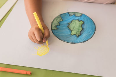 Girl drawing sun on cardboard paper at home