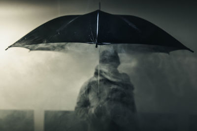 Rear view of man with umbrella standing in rain