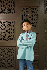 Full length of boy standing against door