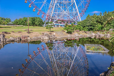 Ferris wheel by lake against blue sky