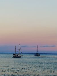 Sailboat sailing on sea against sky during sunset