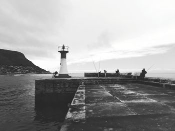 Lighthouse by sea against sky