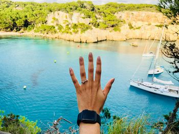 Cropped hand of woman wearing ring and wristwatch against sea