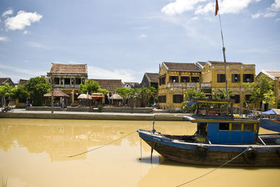 Boats in canal against cloudy sky