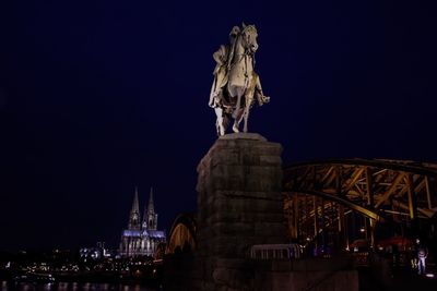 Low angle view of statue by hohenzollernbrucke against sky at night