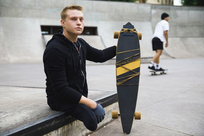 Disabled man sitting with skateboard