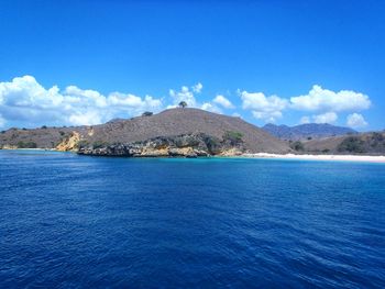 Scenic view of sea by mountain against sky