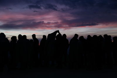 Silhouette people standing against cloudy sky during sunset