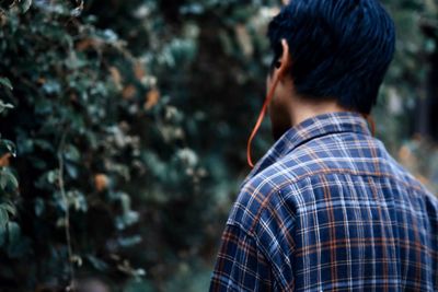 Rear view of man listening music in forest